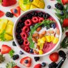 A vibrant, healthy fruit smoothie bowl topped with fresh berries, mango, and almonds.